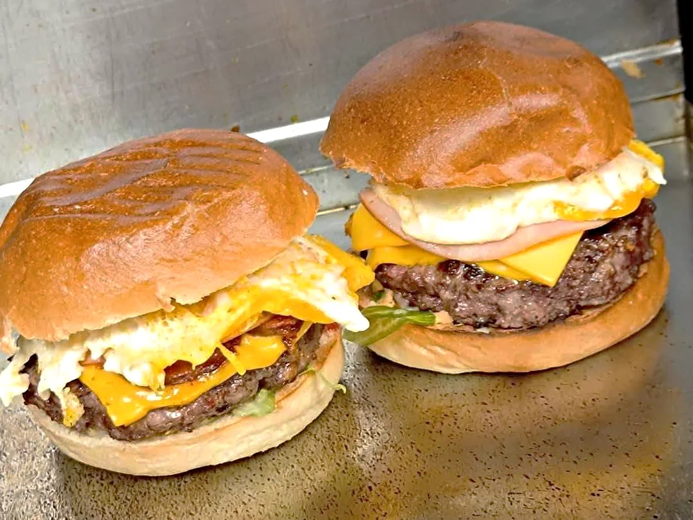 Deux burgers maison sur la plancha, steak, oeuf au plat et cheddar fondu